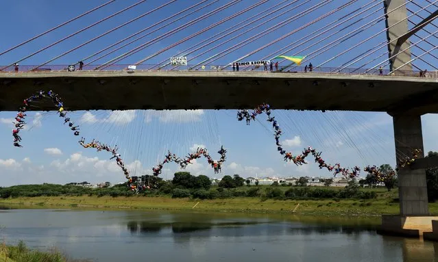 People jump off a bridge, which has a height of 30 meters, in Hortolandia, Brazil, April 10, 2016. (Photo by Paulo Whitaker/Reuters)
