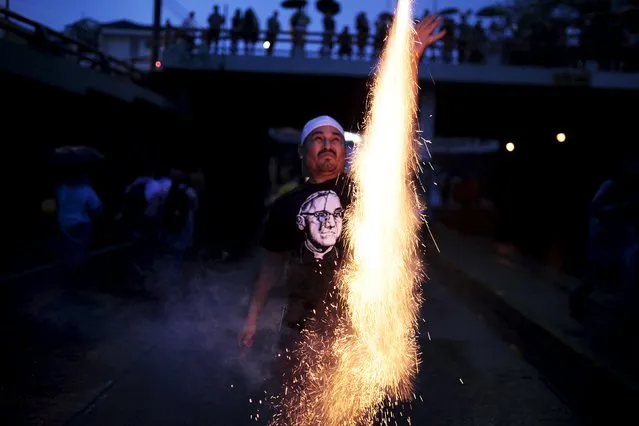 A man launches a firecracker during a procession for the late archbishop of San Salvador Oscar Arnulfo Romero during a procession in San Salvador May 22, 2015. Salvadoran Archbishop Romero, who was murdered by a right-wing death squad in 1980 and is an icon of the Roman Catholic Church in Latin America, had died as a martyr and will be beatified on May 23, the Vatican said. (Photo by Jose Cabezas/Reuters)
