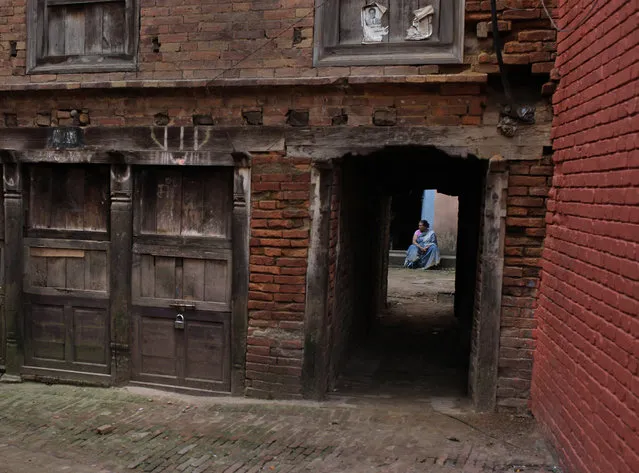 A Nepalese woman sits inside her house in an alley of Bhaktapur, 12 kilometers (7.5 miles) east of Kathmandu, Monday, May 25, 2015, one month after the deadly 7.8 magnitude earthquake hit Nepal. (Photo by Niranjan Shrestha/AP Photo)