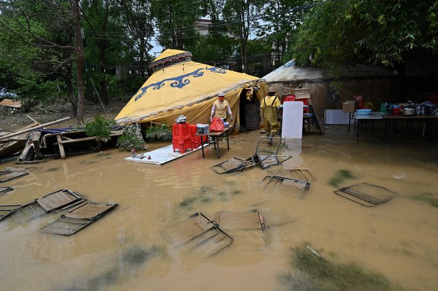 Chairs are submerged as workers collect items after torrential rains flooded the area in Shatang village, in Qingyuan, in northern Guangdong province on April 24, 2024. More than 100,000 people have been evacuated due to heavy rain and fatal floods in southern China, with the government issuing its highest-level rainstorm warning for the affected area. (Photo by Héctor Retamal/AFP Photo)