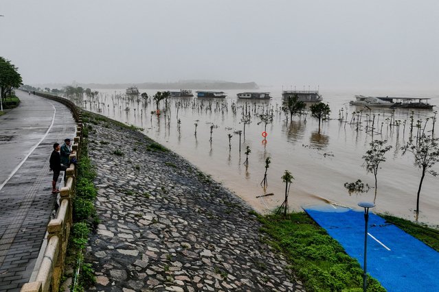 This aerial photograph taken on April 22, 2024 shows people standing on a walkway at a flooded area after heavy rains in Qingyuan, in southern China's Guangdong province. (Photo by AFP Photo/China Stringer Network)