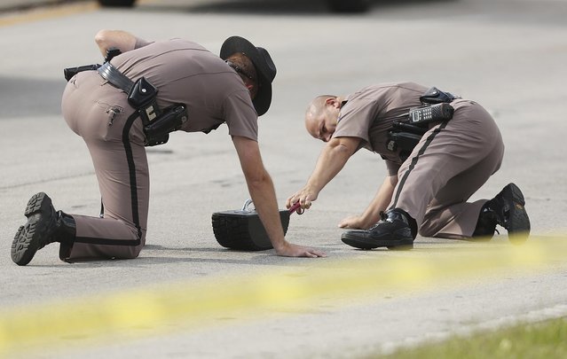 Highway Patrol officers investigate tire skid marks after several children were injured after being struck by a vehicle at a KinderCare Learning Center in Winter Park, Florida April 9, 2014. One child died and a dozen people were injured in a hit-and-run crash at an Orlando-area day care center on Wednesday afternoon, according to media reports citing hospital officials. (Photo by Stephen M. Dowell/Reuters/Orlando Sentinel)