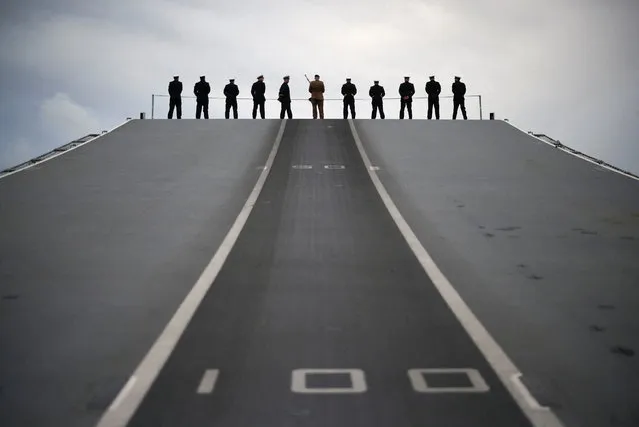 Members of the ships company stand in the “Procedure Alpha” position on the flight deck of the Royal Navy aircraft carrier HMS Queen Elizabeth, as it approaches Her Majesty's Naval Base (HMNB) Portsmouth, following her seven month deployment leading Carrier Strike Group 21, in Portsmouth, Britain, December 9, 2021. (Photo by Henry Nicholls/Reuters)