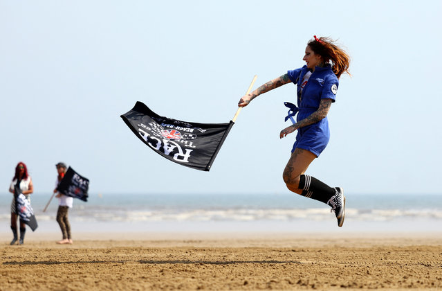 A female starter leaps in the air during “Race The Waves” classic car and motorcycle meet at the beach in Bridlington, Britain, on May 12, 2024. (Photo by Lee Smith/Reuters)