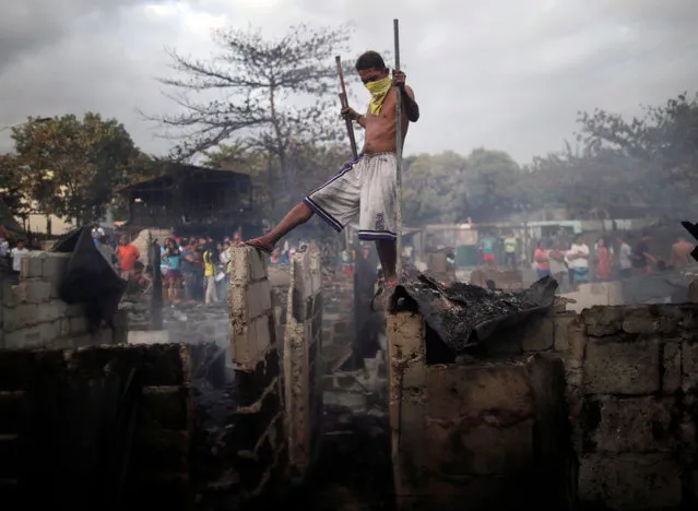 A Filipino informal settler manuevers on top of burnt shanties after a fire at a slum area in Paranaque city, south of Manila, Philippines, 22 February 2019 (issued 13 June 2019). The metropolitan area of Manila has the largest slum area in the world, home to some four million people, a third of the inhabitants of the city, according to studies conducted by humanitarian organization. (Photo by Francis R. Malasig/EPA/EFE)