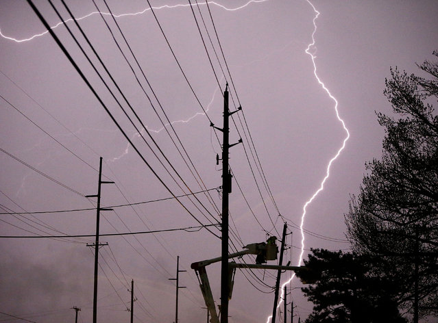 Lightning flashes as a utility crew works on a power line on East 15th Street just west of Sheridan, Okla., Wednesday, March 25, 2015. (Photo by Mike Simons/AP Photo/Tulsa World)