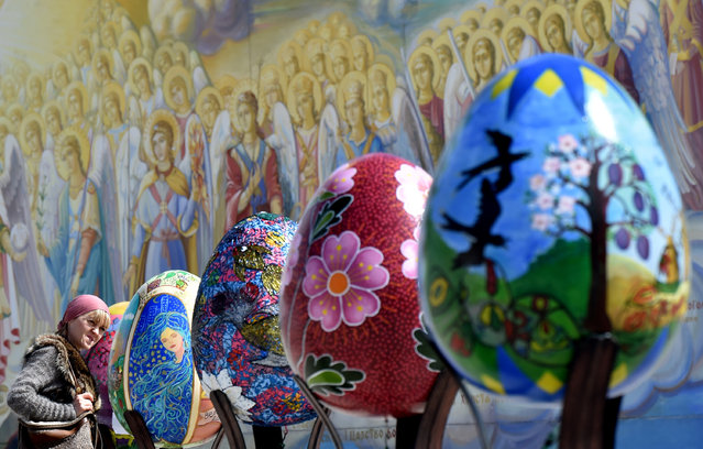 A woman looks at huge Easter eggs as they walk in the open air festival in the center of Kiev on April 12, 2017. (Photo by Sergei Supinsky/AFP Photo)