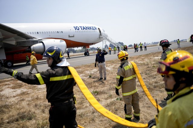 Firefighters load water on to the 10 Tanker plane at the airport as they fight forest fires, in Talcahuano, Chile, Monday, February 6, 2023. Wildfires are spreading in southern and central Chile, triggering evacuations and the declaration of a state of emergency in some regions. (Photo by Matias Delacroix/AP Photo)