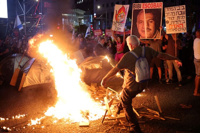 Fire burns as people attend a demonstration against Prime Minister Benjamin Netanyahu's government and a call for the release of hostages in Gaza, amid the Israel-Hamas conflict, in Tel Aviv, Israel on June 15, 2024. (Photo by Marko Djurica/Reuters)