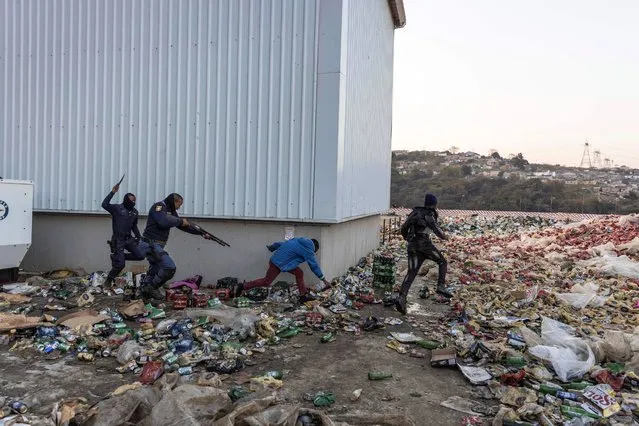 Two members of SAPS chase and shoot rubber bullets at two suspected looters outside a warehouse storing alcohol in Durban on July 16, 2021, in the midst of an ongoing alcohol ban after protestors have clashed with police following a week of unrest in South Africa. South African President Cyril Ramaphosa said that those behind the riots and violence that have shaken the country and claimed 212 lives in the past week had sought to foment an “insurrection”. “Those behind these acts have sought to provoke a popular insurrection amongst our people”, he said in a televised address. (Photo by Guillem Sartorio/AFP Photo)
