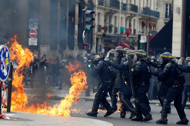 French CRS riot police protect themselves from flames during clashes at the traditional May Day labour union march in Paris on May 1, 2017. (Photo by Gonzalo Fuentes/Reuters)