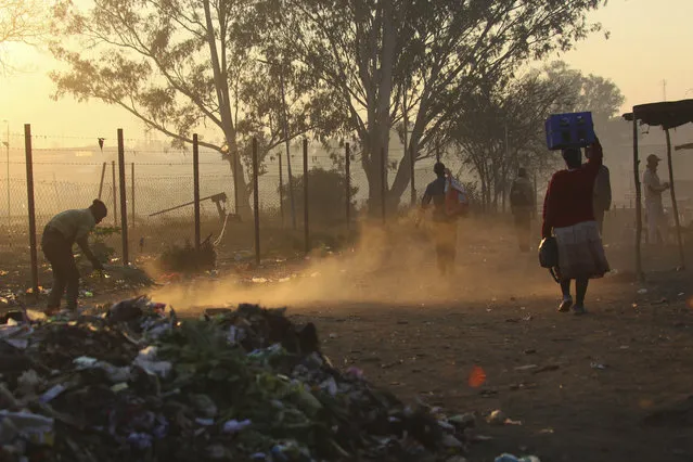 A man sweeps a path near a dumpsite in Harare, Thursday, August 8, 2019. Many Zimbabweans who cheered the downfall of longtime leader Robert Mugabe two years ago have found the country's economy even worse than before. (Photo by Tsvangirayi Mukwazhi/AP Photo)