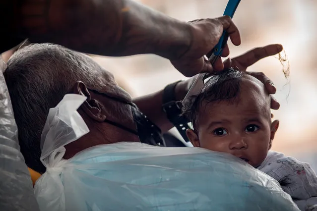 A barber shaves the hair of a Hindu baby to complete one of the religious rituals during the Thaipusam celebration in Selangor, Malaysia on January 18, 2022. The National Security Council has allowed the celebration to be held in strict adherence to the Standard Operation Procedure (SOP) to curb Covid-19 infection and there are some other rituals such as carrying “kavadi” and drum performances are not allowed. (Photo by Syaiful Redzuan/Anadolu Agency via Getty Images)