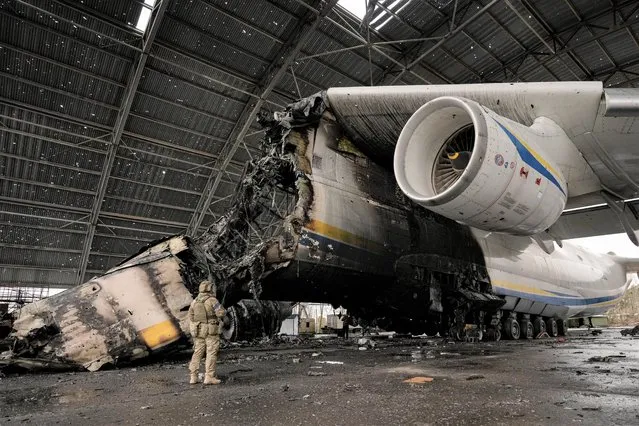 A Ukrainian serviceman walks by an Antonov An-225 Mriya aircraft destroyed during fighting between Russian and Ukrainian forces at the Antonov airport in Hostomel, Ukraine, Saturday, April 2, 2022. At the entrance to Antonov Airport in Hostomel Ukrainian troops manned their positions, a sign they are in full control of the runway that Russia tried to storm in the first days of the war. (Photo by Vadim Ghirda/AP Photo)