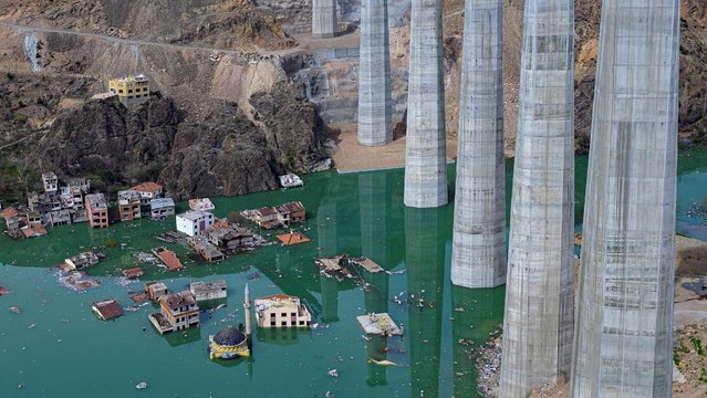 A photograph taken on April 4, 2023 shows pilars and buildings in the rising water of an artificial lake which gradually submerges the village of Yusufeli as it retains the flow of the Coruh river (also referred to as Chorokhi), in Artvin province, in northeastern Turkey. The Yusufeli Dam and its Hydroelectric Power Plant Project in the Eastern Black Sea Region has started to hold water, with the electricity production expected to start in May 2023. With a total water storage volume of approximately 2.2 billion cubic meters, the double curvature concrete arch dam is Turkeys highest with a height of 275 meters. (Photo by Yasin Akgul/AFP Photo)