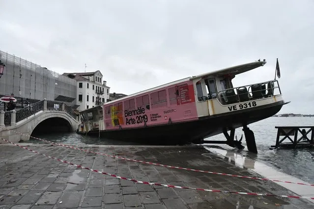 A stranded ferry boat lies on its side, in Venice, Wednesday, November 13, 2019. The mayor of Venice is blaming climate change for flooding in the historic canal city that has reached the second-highest levels ever recorded, as another exceptional water level was recorded Wednesday. The high-water mark hit 187 centimeters (74 inches) late Tuesday, meaning more than 85% of the city was flooded. (Photo by Luigi Costantini/AP Photo)