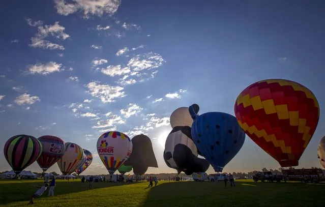 Hot air balloons are inflated at sunrise on day one of the 2015 New Jersey Festival of Ballooning in Readington, New Jersey, July 24, 2015. More than 100 hot air balloons are taking part in the three-day festival, one of the largest of it's kind in North America, according to organizers. (Photo by Mike Segar/Reuters)
