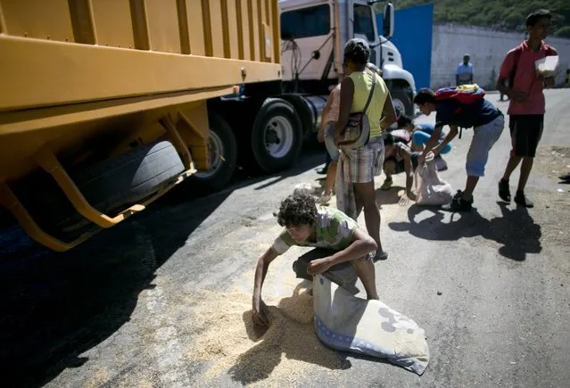 In this November 14, 2016 photo, a youth uses his pillow as a bag to collect rice from the pavement that shook loose from a food cargo truck waiting to enter the port in Puerto Cabello, Venezuela, the port that handles the majority of Venezuela's food imports. As millions of Venezuelans go hungry this year, food trafficking has become one of the most lucrative businesses in the country. (Photo by Ariana Cubillos/AP Photo)