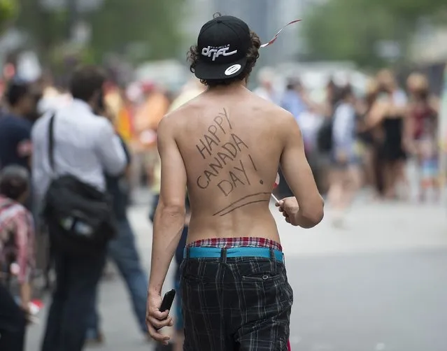 A man with a Canada Day message on his back looks on during the annual Canada Day parade in Montreal, Tuesday, July 1, 2014. (Photo by Graham Hughes/The Canadian Press)
