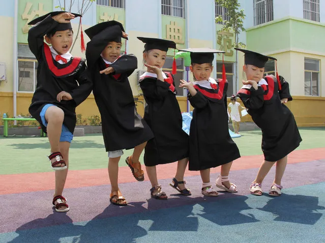 Children in gowns and mortarboards pose for pictures during their kindergarten graduation ceremony, in Wenxian county, Henan province July 2, 2014. (Photo by Reuters/Stringer)