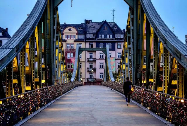 A woman walks over the “Eiserner Steg” (iron footbridge) decorated with love locks in downtown Frankfurt, Germany, early Tuesday, September 7, 2021. (Photo by Michael Probst/AP Photo)