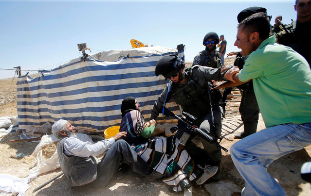 Palestinians scuffle with an Israeli border policeman as Israeli troops demolish sheds belonging to Palestinians near the West Bank village of Yatta, south of Hebron June 19, 2016. (Photo by Mussa Qawasma/Reuters)