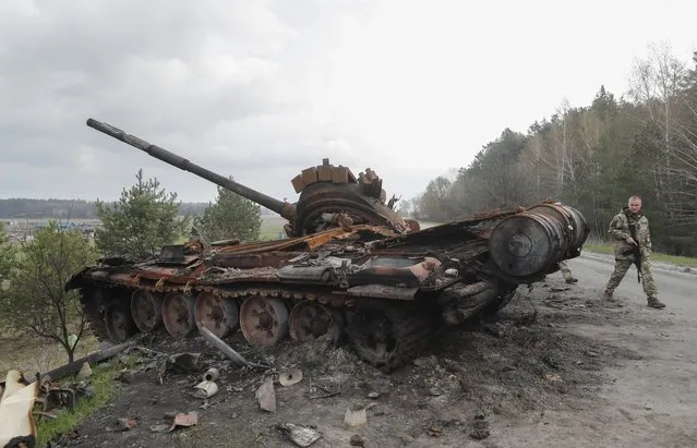 Ukrainian serviceman walks next to a destroyed Russian tank in Rusaniv, outskirts of Kyiv, Ukraine, 16 April 2022. Russian troops entered Ukraine on 24 February resulting in fighting and destruction in the country, and triggering a series of severe economic sanctions on Russia by Western countries. (Photo by Sergey Dolzhenko/EPA/EFE)
