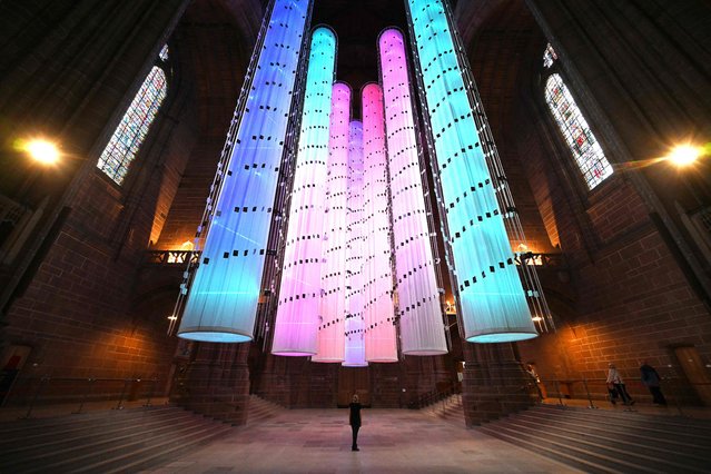 An artwork, “Identity” by sculptor Peter Walker is seen as it is installed in Liverpool Cathedral on July 27, 2023 in Liverpool, north west England. The final chapter of the Identity – we are all together series, following the success of “Peace Doves” and 'Being Human' will be on display until September 3. The seven illuminated columns are lit with individual strips of light representing the double helix of DNA and demonstrating the unique make up of each person. The columns are wrapped in more than 3000 individual portraits potographed as part of Peter Walker's 2022 installation “Being Human”. (Photo by Paul Ellis/AFP Photo)