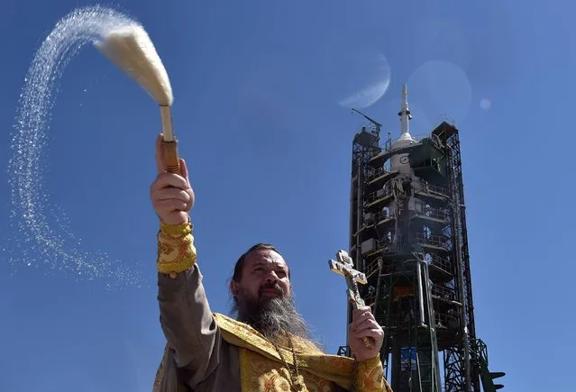 A Russian Orthodox priest conducts a blessing in front of the Soyuz MS-05 spacecraft set, by the launch pad of the Russian leased Baikonur cosmodrome in Kazakhstan, on July 27, 2017. The launch of the Soyuz MS-05 rocket, which will take three astronauts : American Randy Bresnik, Italian Paolo Nespoli and Russian Sergey Ryazansky, to the International Space Station is scheduled on July 28, 2017. (Photo by Vyacheslav Oseledko/AFP Photo)