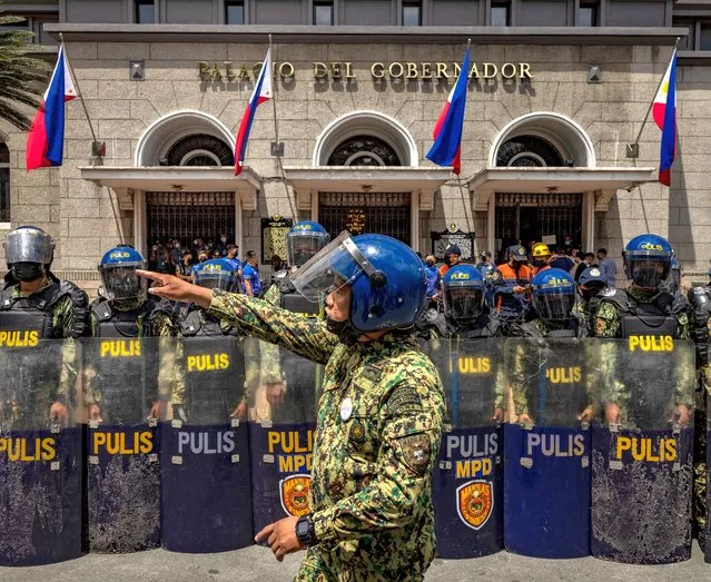 Police officers stand guard as Filipinos take part in a protest against election results outside the Commission on Elections building on May 10, 2022 in Manila, Philippines. Ferdinand “Bongbong” Marcos Jr. is poised to win the presidency in a hotly contested election marred by several incidents of violence and numerous complaints of faulty vote counting machines. Marcos, the son and namesake of ousted dictator Ferdinand Marcos Sr. who was accused and charged of amassing billions of dollars of ill-gotten wealth as well as committing tens of thousands of human rights abuses during his autocratic rule, mounted a hugely popular campaign based largely on disinformation to return his family name to power. Election results a day after millions of Filipinos went to polls show Marcos enjoying a massive lead against main rival Vice President Leni Robredo. Also poised to win the vice presidency is Mayor Sara Duterte of Davao City, the daughter of outgoing President Rodrigo Duterte who is the subject of an international investigation for alleged human rights violations during his war on drugs. (Photo by Ezra Acayan/Getty Images)