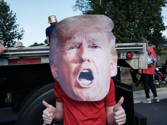 A 11-year-old boy poses with a mask of former US President and Republican presidential candidate Donald Trump that was purchased at a Halloween store before a campaign rally outside Christ Chapel in Zebulon, Georgia, on October 23, 2024. (Photo by Yasuyoshi Chiba/AFP Photo)