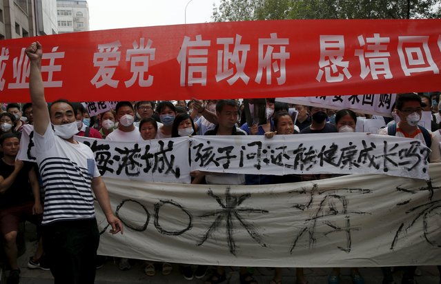 Residents who evacuated from their homes after last week's explosions at Binhai new district, take part in a rally demanding government compensation outside the venue of the government officials' news conference in Tianjin, China, August 17, 2015. White banner reads “Children ask: can we still grow up healthy?”. (Photo by Kim Kyung-Hoon/Reuters)