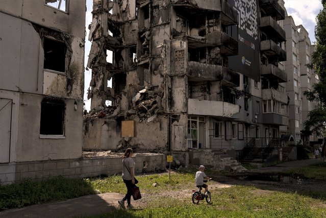 A woman and a boy make their way past an apartment building destroyed in Russian attacks in Borodyanka, Ukraine, Wednesday, August 2, 2023. Borodyanka was occupied by Russian troops at the beginning of their full-scale invasion last year. (Photo by Jae C. Hong/AP Photo)