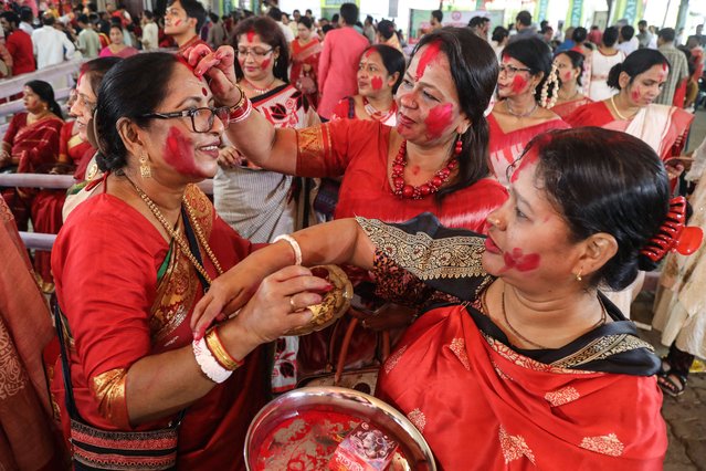 Devotees take part in a ritual 'Sindoor Khela' wherein married women anoint each other with vermilion powder ahead of the immersion of Hindu goddess “Durga” idols during the Hindu festival of “Durga Puja” in Dhaka on October 13, 2024. (Photo by Abdul Goni/AFP Photo)