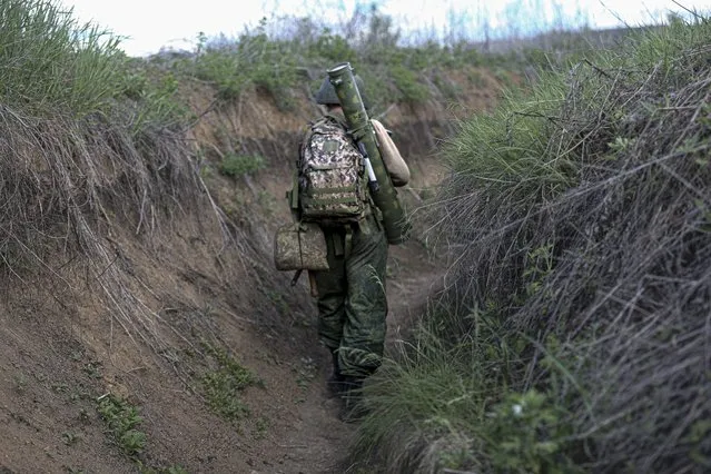 A serviceman of Donetsk People's Republic militia walks along a trench at the position not far from a frontline outside Vasylivka village in Yasynuvata district in territory under the government of the Donetsk People's Republic, eastern Ukraine, Monday, May 16, 2022. (Photo by Alexei Alexandrov/AP Photo)