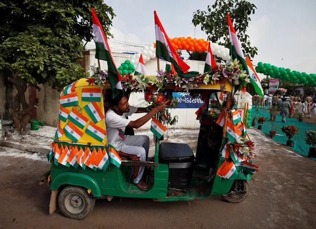 A man decorates an auto rickshaw with the national flags to celebrate India's Independence Day in Ahmedabad, August 15, 2017. (Photo by Amit Dave/Reuters)