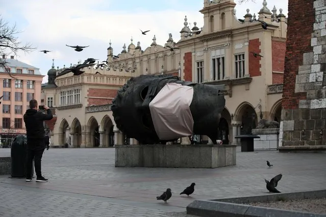 A sculpture Eros Bendato with a mock mask is seen on the main square during the coronavirus disease (COVID-19) lockdown in Krakow, Poland, March 23, 2020. (Photo by Jakub Wlodek/Agencja Gazeta via Reuters)