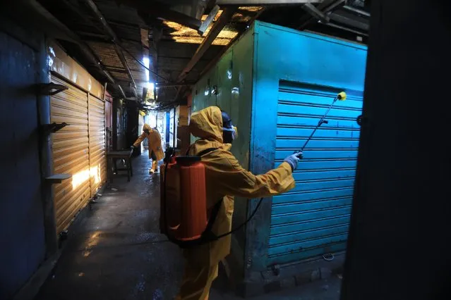 A member of a local hygiene service wearing a protective suit and a face mask disinfects a market to stop the spread of coronavirus disease (COVID-19) in Port Bouet, a neighbourhood of Abidjan, Ivory Coast, March 30, 2020. (Photo by Thierry Gouegnon/Reuters)