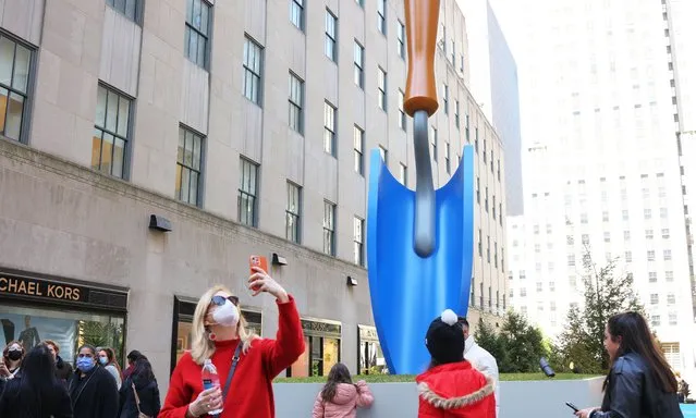 People walk past the “Plantoir, Blue“ sculpture iat the Channel Gardens in Rockefeller Center on March 22, 2022 in New York City. A sculpture titled “Plantoir, Blue” by artists Claes Oldenburg And Coosje Van Bruggen officially opened to the public today at Rockefeller Center. The sculpture, which is the first public installation in New York City in more than 20 years for the artists, will be on view from March 18 through May 6, 2022. (Photo by Michael M. Santiago/Getty Images)