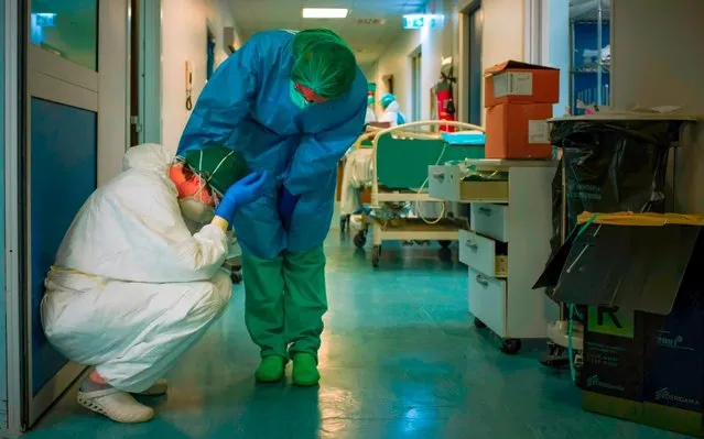 A nurse wearing protective mask and gear comforts another as they change shifts on March 13, 2020 at the Cremona hospital, southeast of Milan, Lombardy, during the country's lockdown aimed at stopping the spread of the COVID-19 (new coronavirus) pandemic. After weeks of struggle, they're being hailed as heroes. But the Italian healthcare workers are exhausted from their war against the new coronavirus. (Photo by Paolo Miranda/AFP Photo)