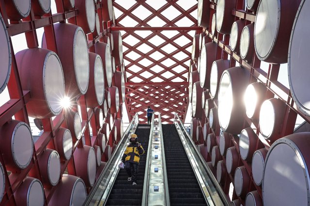People take an escalator amid an installation of drums in Beijing on January 3, 2025. (Photo by Jade Gao/AFP Photo)