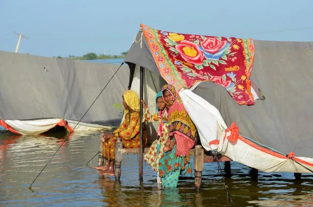 Flood victim family take refuge with their belongings as floodwater rises, following rains and floods during the monsoon season in Sohbatpur, Pakistan on September 4, 2022. (Photo by Amer Hussain/Reuters)
