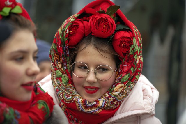 Young women watch people plunging into icy water during celebrations of Epiphany in Kyiv, Ukraine, Monday, January 6, 2025. (Photo by Efrem Lukatsky/AP Photo)