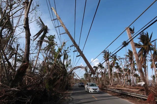 Cars drive under a partially collapsed utility pole, after the island was hit by Hurricane Maria in September, in Naguabo, Puerto Rico October 20, 2017. (Photo by Alvin Baez/Reuters)