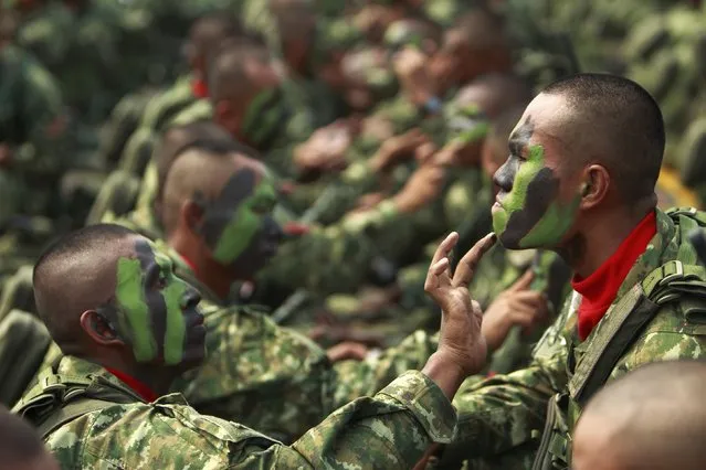 Indonesia's Airborne 328 soldier help one another apply camouflage paint on their faces before a ceremony to mark the 67th anniversary of the Indonesian National Military at the tarmac of Halim Perdanakusuma airport in Jakarta October 5, 2012. (Photo by Beawiharta/Reuters)