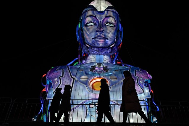 People walk past a figure at a park during the Lantern festival in Beijing on February 12, 2025. (Photo by Pedro Pardo/AFP Photo)