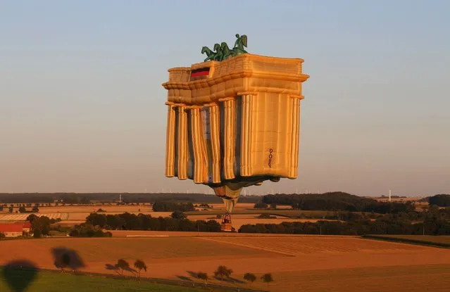 A hot-air balloon in the shape of Berlin's Brandenburg Gate flies over fields near Bad Sassendorf, western Germany, on August 18, 2016. It was the last flight of the balloon that was built on the occasion of the German reunification. Due to its age-related material weakness, the balloon has to be taken out of service now. (Photo by Jorg Taron/AFP Photo)