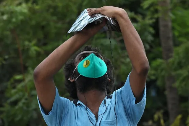 A man, wearing a protective face mask against the coronavirus disease (COVID-19), uses his mobile phone and a filter to take photographs of a partial solar eclipse in Kolkata, India, June 21, 2020. (Photo by Rupak De Chowdhuri/Reuters)