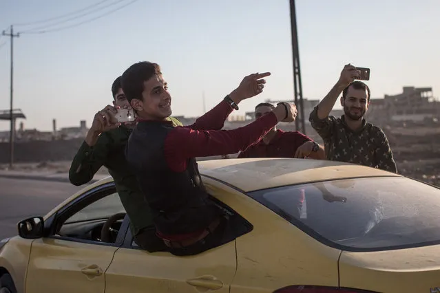 Men dance and sing from a car as they celebrate a wedding in West Mosul on November 3, 2017 in Mosul, Iraq. Five months after Mosul, Iraq's second-largest city was liberated from ISIL in a nine-month long battle, residents have returned to the destroyed city to rebuild their lives. After more than two years of ISIL occupation, savage fighting, airstrikes and as ISIL fighters retreated they intentionally destroyed remaining key infrastructure such as bridges, government buildings, water and sewage facilities and neighborhoods laced with booby traps and homemade bombs leaving the city in ruins. Despite the damage residents have hastily returned and managed to setup temporary shops, homes and services to help bring the city back to life. In West Mosul, home to the Old City, more than 32,000 homes were destroyed and a recent report from the U.N. estimates repairing Mosul's basic infrastructure will cost more than $1 billion and take years to complete. (Photo by Chris McGrath/Getty Images)
