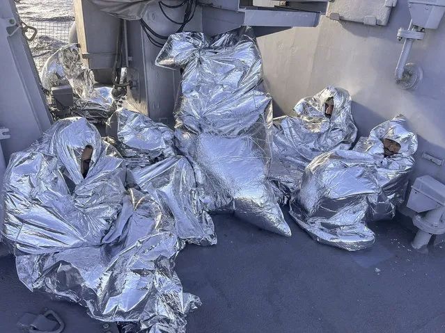 In this photo provided by the Greek Coast Guard, some of the nine men who survived a shipwreck and were found on an uninhabited islet are covered with a thermal blankets as they sit aboard a Greek Coast guard vessel, in the Aegean Sea, Greece, on Tuesday, November 1, 2022. A major search and rescue operation was underway Tuesday for dozens of people missing after the boat they were on capsized and sank in stormy weather overnight off the coast of an island near the Greek capital. The coast guard said nine survivors, all men, had been found on an uninhabited islet south of the island of Evia and had been picked up by a coast guard vessel. (Photo by Greek Coast Guard via AP Photo)